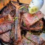 Close-up of Peter Luger style steak slices glistening with garlic butter