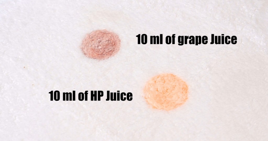 Two stains on a white carpet, one grape juice and one Hawaiian Punch, used in stain removal tests to simulate common pet stains for carpet shampooer evaluations.