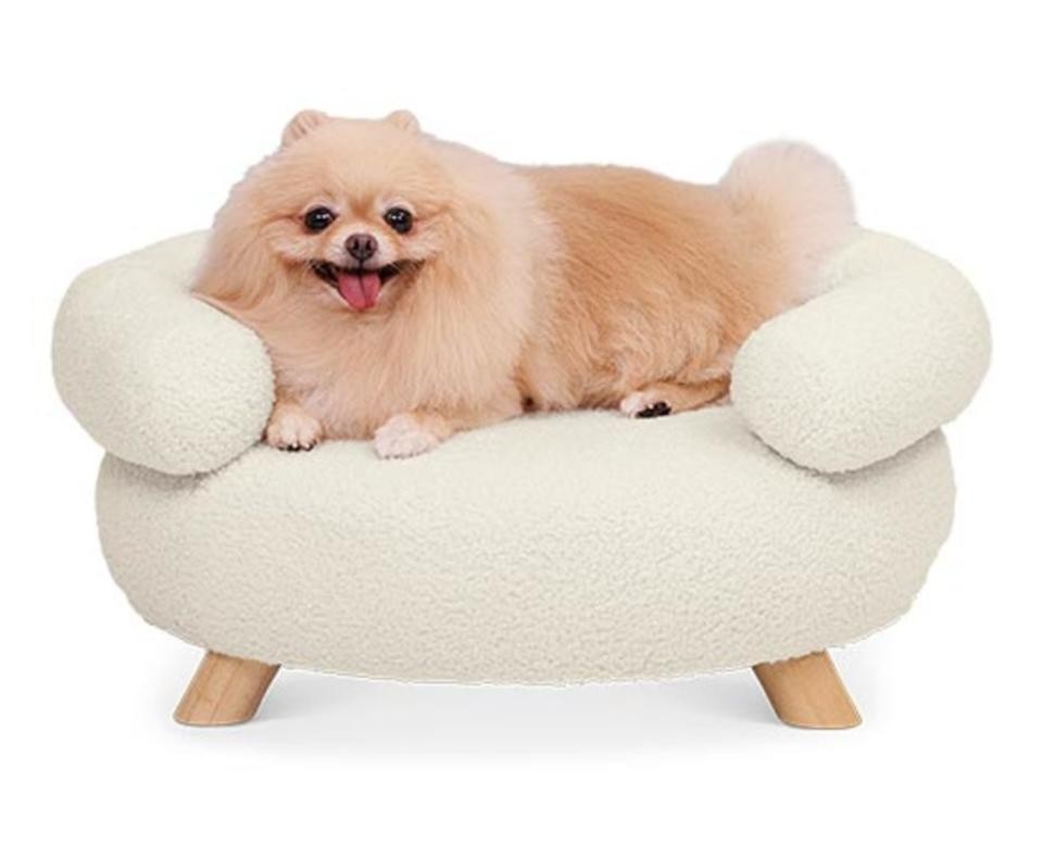 Aldi Heart to Tail Luxury Pet Sofa in Boucle fabric, showcasing its oval shape and wooden legs.