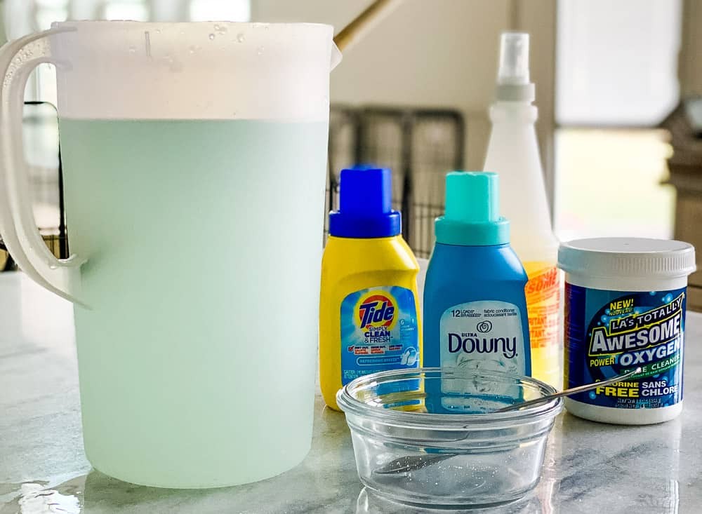 ส่วนผสมสำหรับสูตรอาหาร ได้แก่ oxiclean, tide, downy และ awesome cleaner พร้อมเหยือกที่บรรจุสารละลายสีฟ้าอ่อน