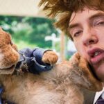 Thomas McGregor getting kicked by Peter Rabbit in Peter Rabbit 2 The Runaway, showcasing the slapstick comedy of the Peter Rabbit movies