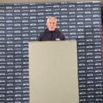 Pete Carroll at a press conference, speaking to a crowd of reporters.