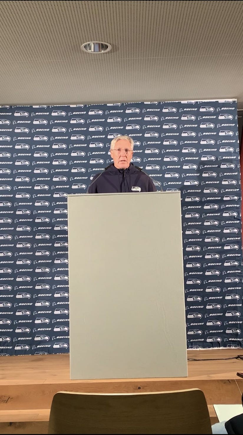 Pete Carroll at a press conference, speaking to a crowd of reporters.