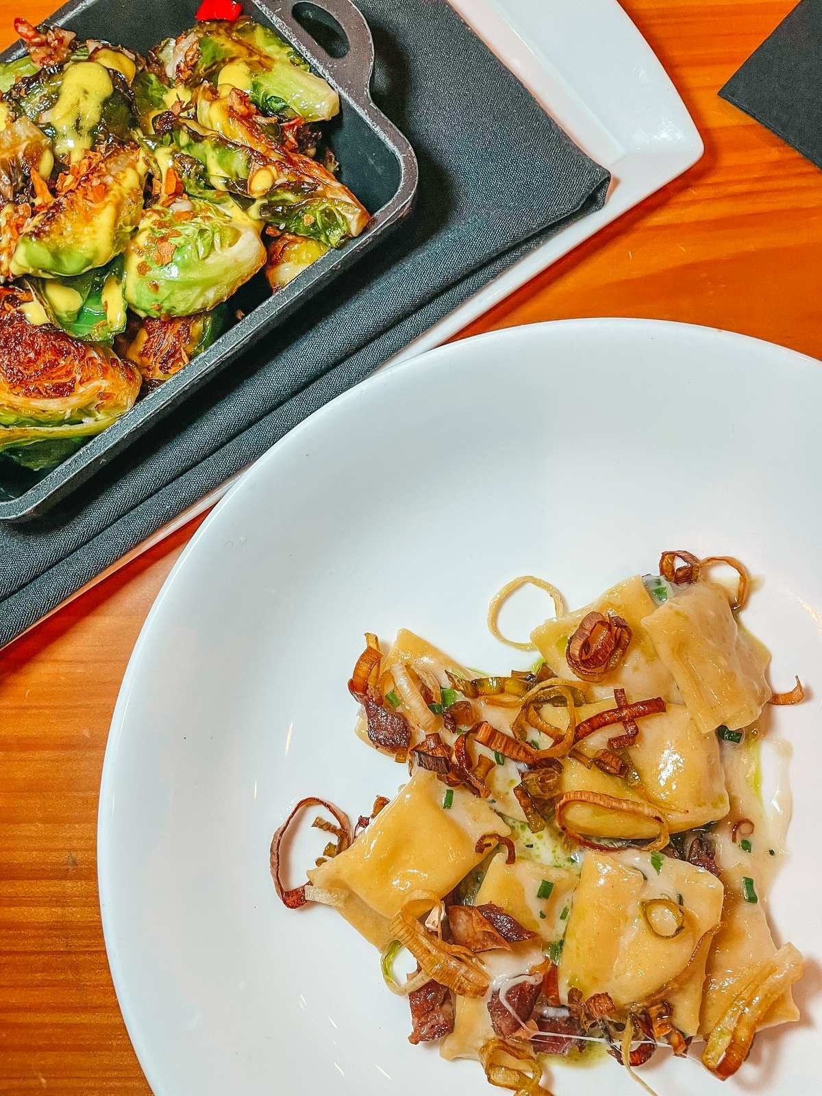 A close-up shot of Taleggio Agnolotti pasta dish at Il Ritorno downtown st pete dining, showcasing tender pasta, lamb belly, charred leeks, and chive oil