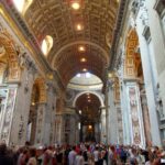 Interior of St. Peter's Basilica showcasing the nave, arches, and ornate decorations, exemplifying its vastness and artistic richness.