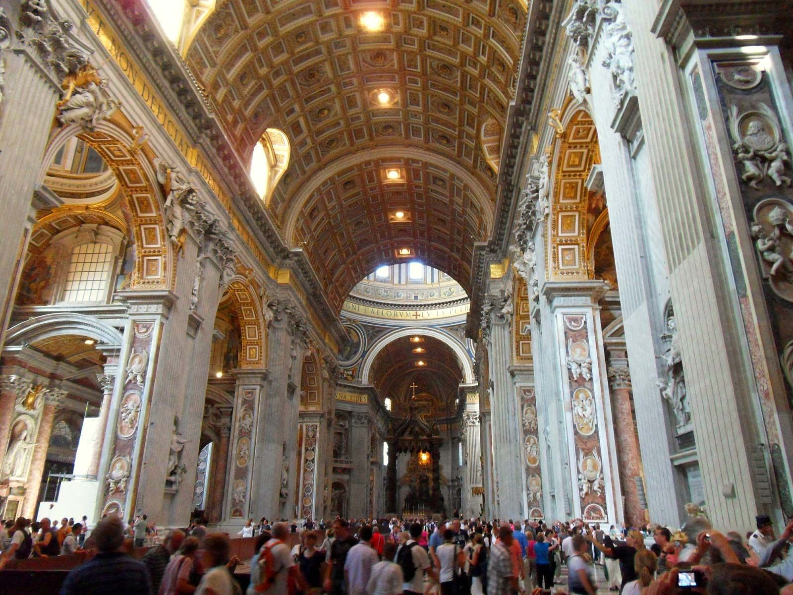 Interior of St. Peter's Basilica showcasing the nave, arches, and ornate decorations, exemplifying its vastness and artistic richness.