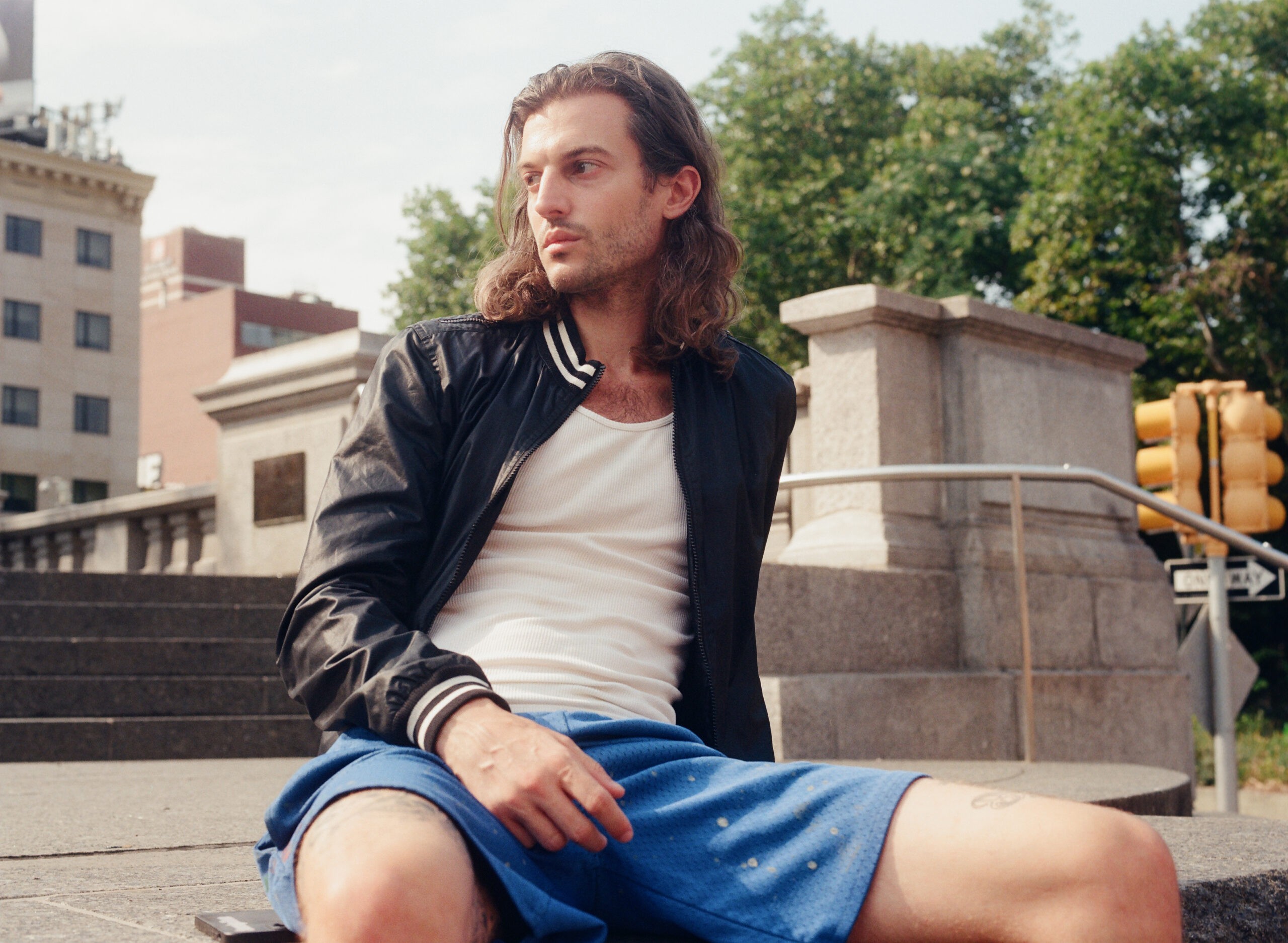 Peter Vack photographed in a casual pose, highlighting his braided hair and informal attire, reflecting a relaxed and creative persona.