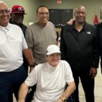 Pete Rose in a wheelchair alongside baseball legends Dave Concepcion, George Foster, Tony Perez, and Ken Griffey Sr., symbolizing a final gathering of baseball greats.