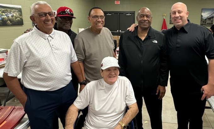 Pete Rose in a wheelchair alongside baseball legends Dave Concepcion, George Foster, Tony Perez, and Ken Griffey Sr., symbolizing a final gathering of baseball greats.