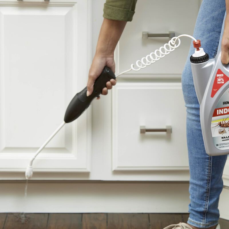 Close-up view of Ortho Home Defense being sprayed along an indoor baseboard, demonstrating the application method for interior pest control.