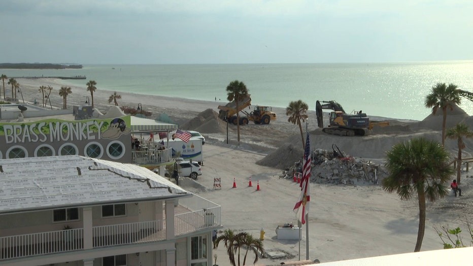 Coastal view of St. Pete Beach, Florida, showcasing the aftermath of a hurricane near Hurricane Restaurant, with sand dunes reaching building height illustrating the storm's impact and ongoing recovery efforts.