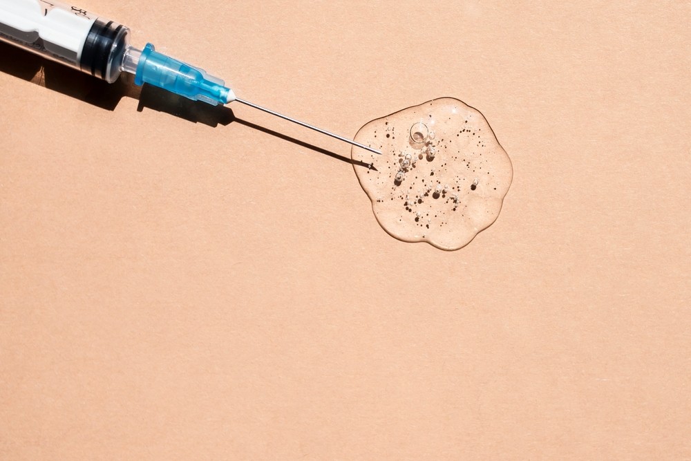 Thin needle in a transparent gel-like liquid with bubbles on a beige background