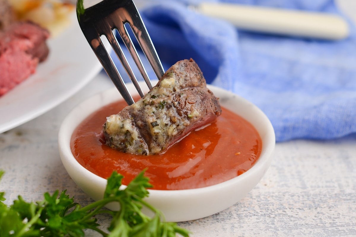 Image showcasing a steak being dipped into a bowl of homemade sauce